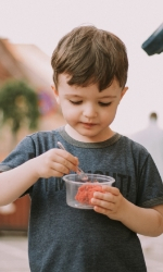 Child eating food out of a plastic cup.